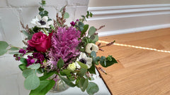 A cool mix of purple and white flowers including ornamental cabbage, rose, anemone and scented stock.